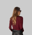 Person wearing a red top and black wide-leg pants against a white wall.